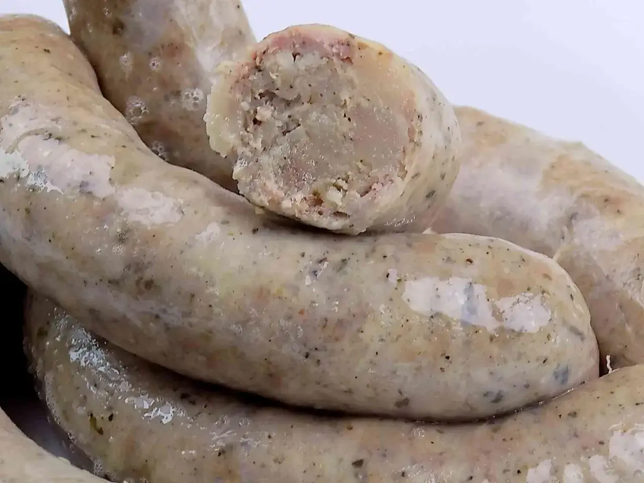 Biała kiełbasa przepis na pyszne, domowe wędliny. Widok na przekrojoną kiełbasę z widocznym farszem.