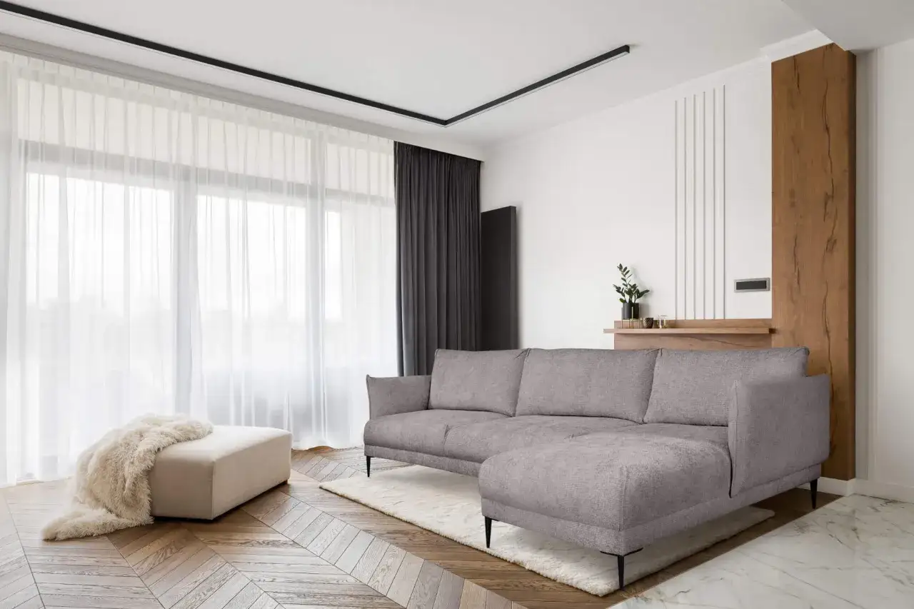 Jasne ściany idealnie komponują się z białymi meblami i szarą kanapą, tworząc przestronne i nowoczesne wnętrze.