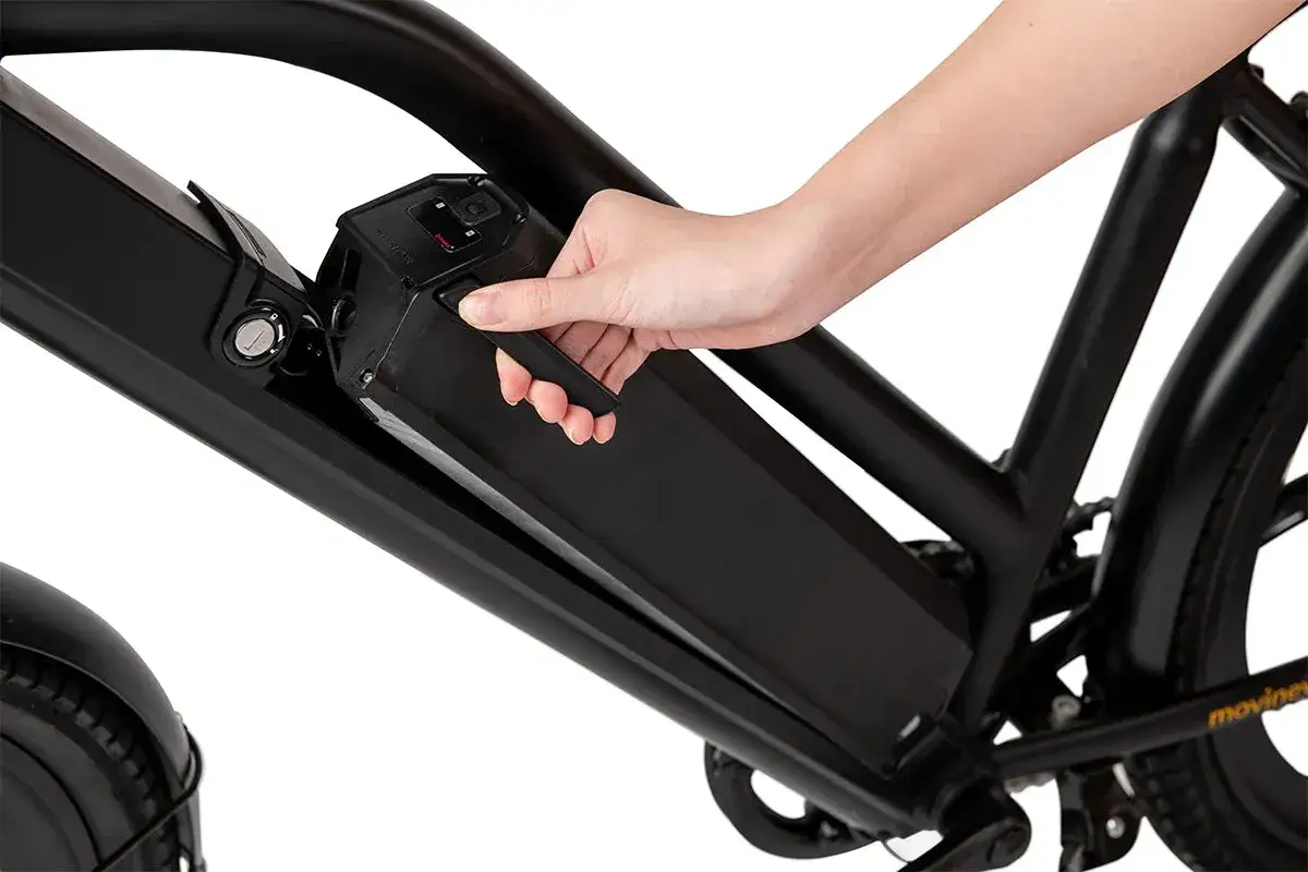 Dłoń wyjmuje czarną baterię z ramy roweru elektrycznego. To pierwsze ładowanie baterii rowerowej, gotowej do drogi.