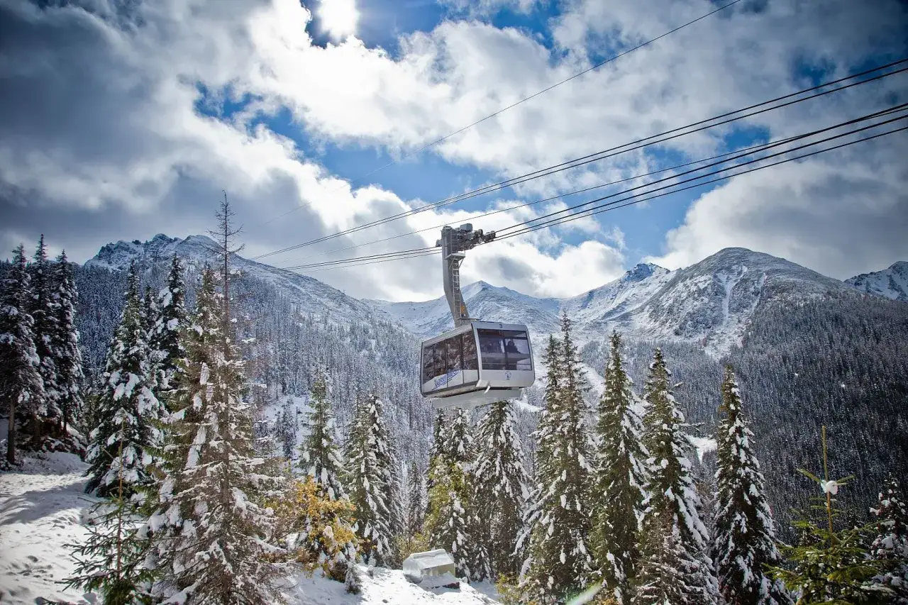 Kolejka linowa wjeżdża na Kasprowy Wierch, otoczona ośnieżonymi świerkami i majestatycznymi szczytami Tatr.