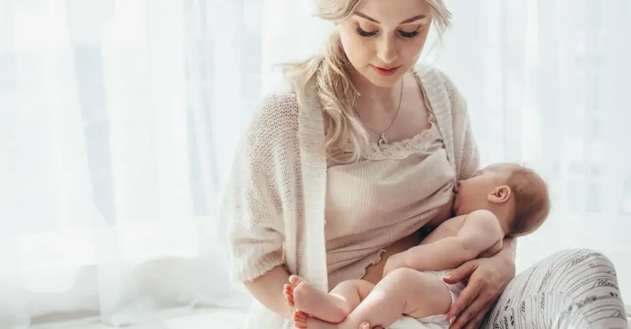 Piękna mama karmi piersią w miejscu publicznym, tworząc intymną chwilę z dzieckiem.