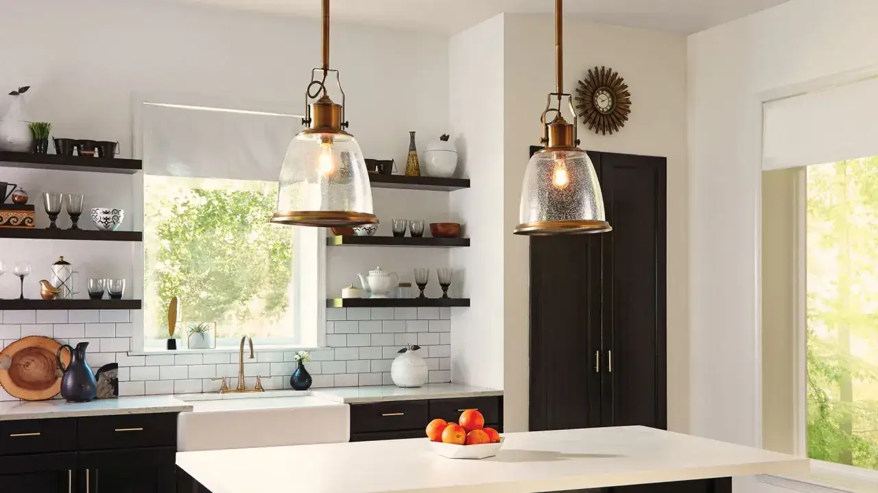 Dwie lampy nad wyspę loft z mosiężnymi elementami i szklanymi kloszami, wiszące nad blatem w nowoczesnej kuchni.