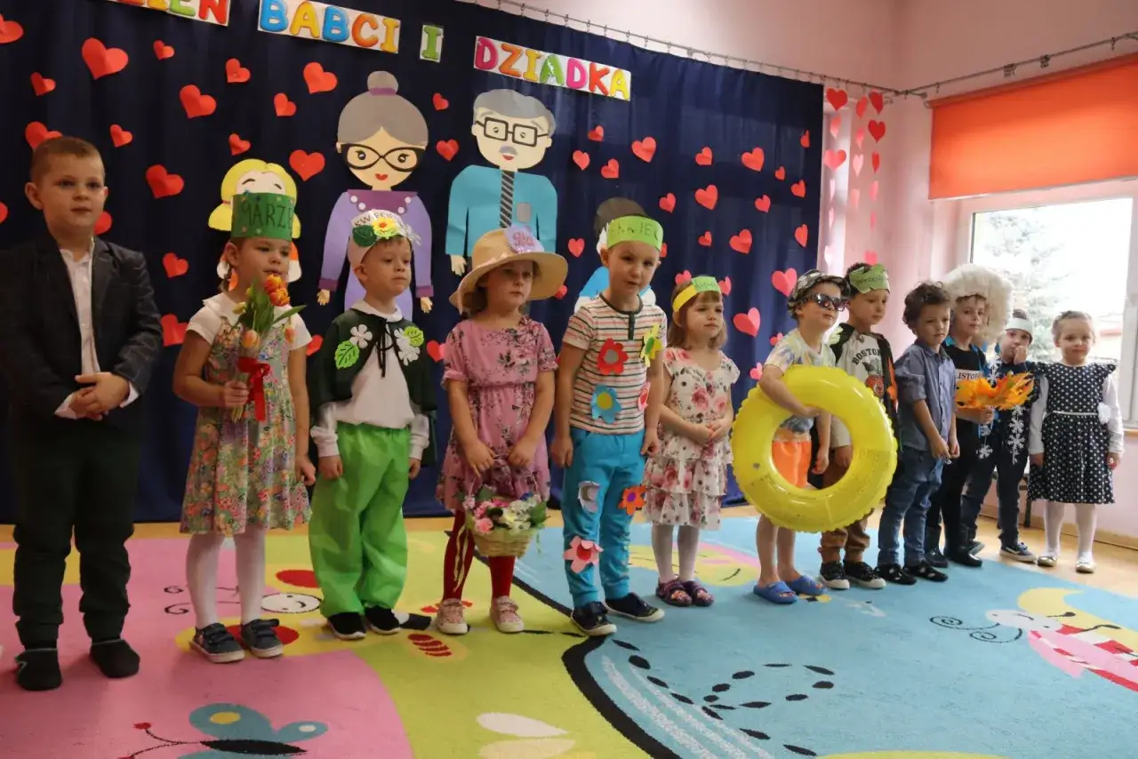 Dzieci w przedszkolu świętują Dzień Babci i Dziadka. Wesoły scenariusz, dzieci w strojach, z kwiatami i zabawkami.