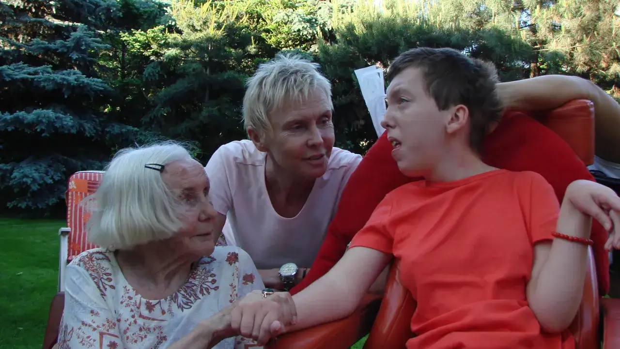 Trzy kobiety, w tym starsza pani i młoda osoba, siedzą razem. Córka Ewy Błaszczyk nie żyje, ale pamięć o niej trwa.