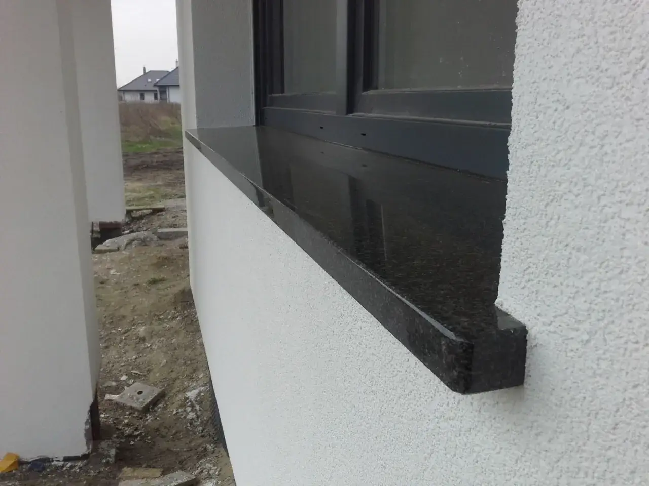 Elegancki, czarny parapet z granitu podkreśla nowoczesną elewację. Czy parapet jest konieczny? Z pewnością dodaje stylu i funkcjonalności.