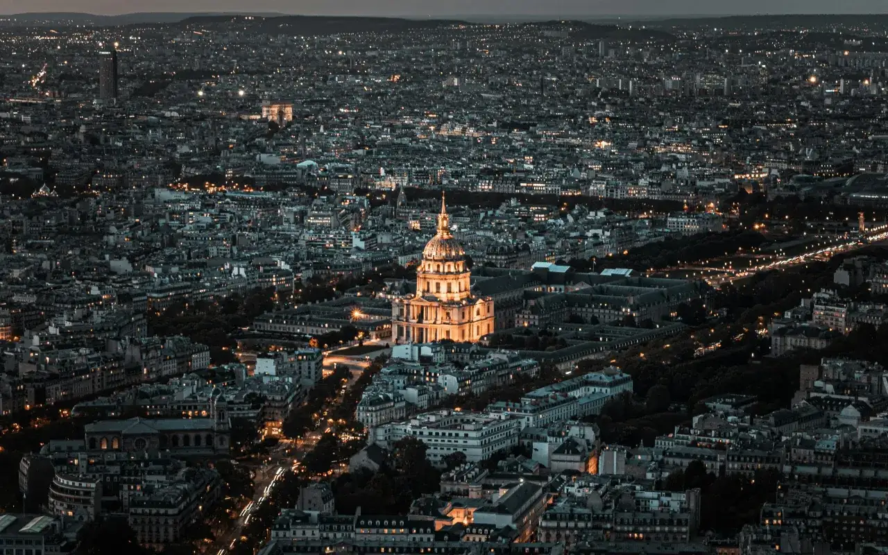 Widok nocny na Paryż z oświetlonym kompleksem Les Invalides. Miasto rozświetlone tysiącami świateł tworzy magiczny krajobraz.