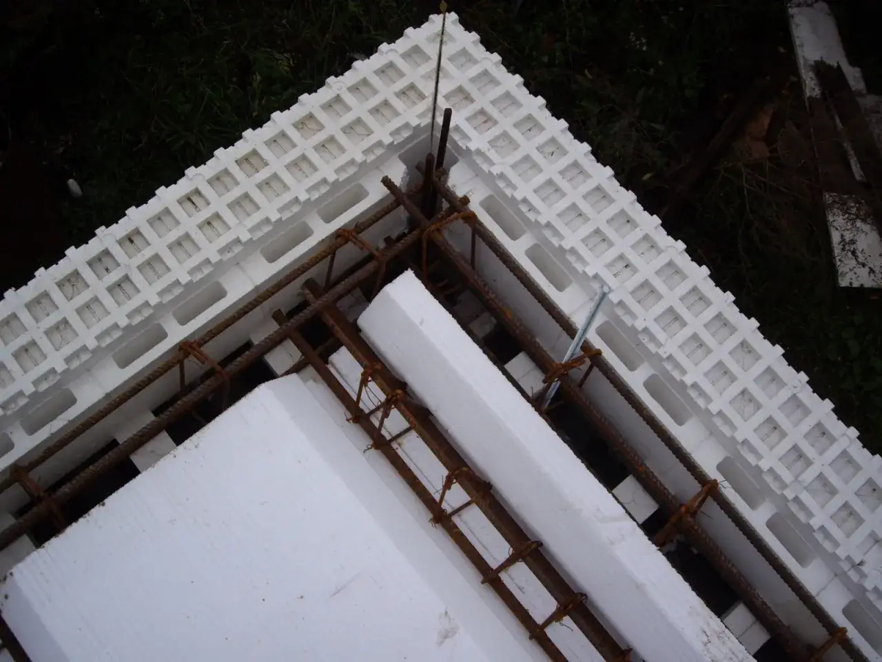 Budowa domu ze styropianu w toku. Widoczne elementy zbrojenia i formy styropianowe tworzące konstrukcję.