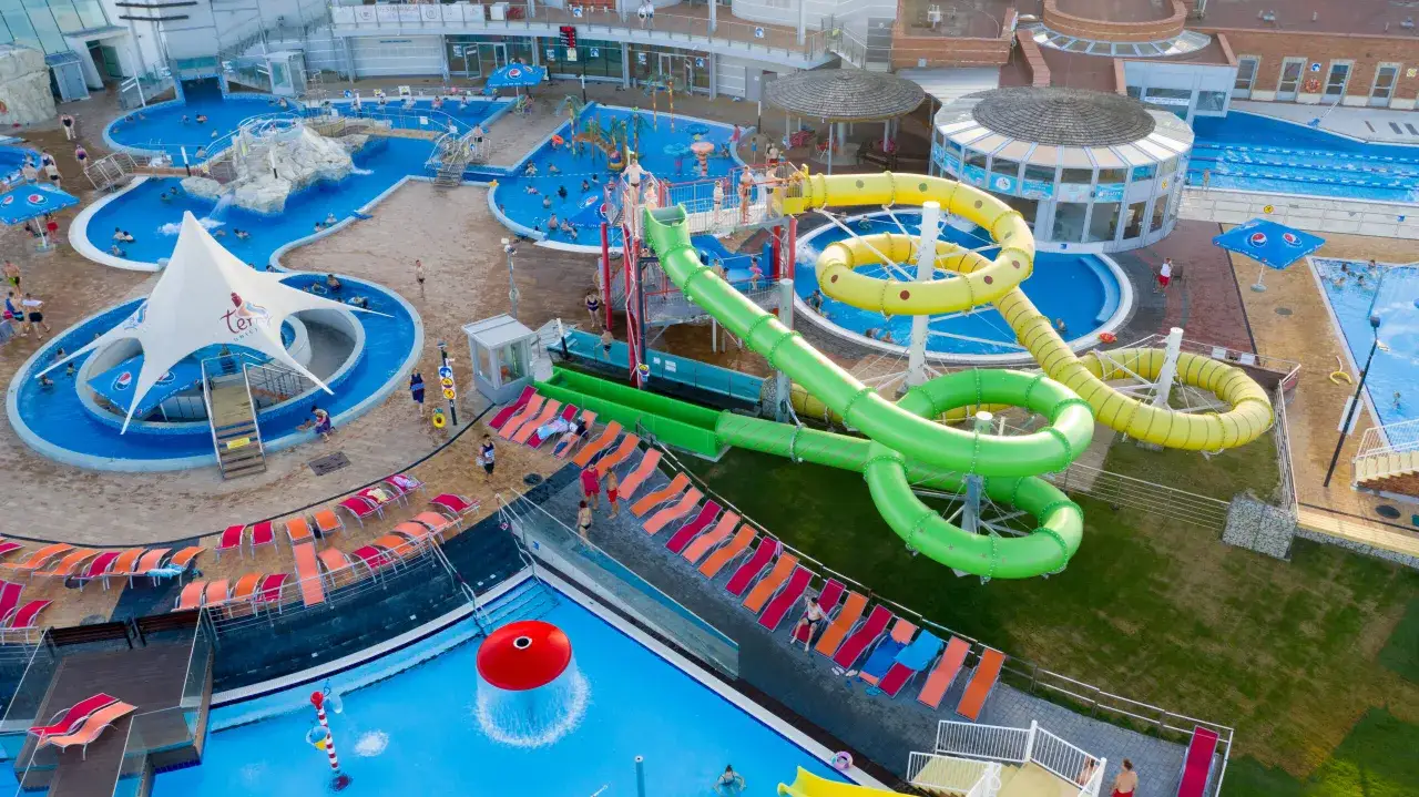 Gdzie są Termy Uniejów? To kompleks basenów i zjeżdżalni wodnych, gdzie ludzie odpoczywają i bawią się w wodzie.