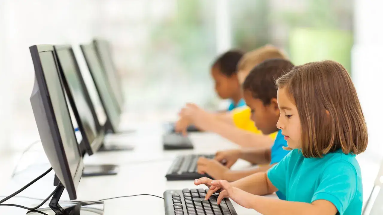 Dzieci uczą się matematyki online, skupione na ekranach komputer&oacute;w.