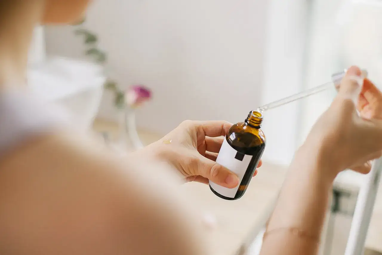 Kobieta aplikuje serum z niacynamidem na dłoń. Bezpieczna pielęgnacja dla przyszłych mam.