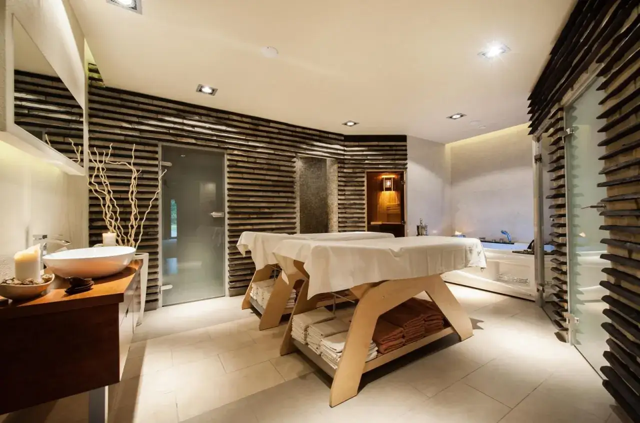 Dwa łóżka do masażu czekają na parę na romantyczny weekend dla dwojga w Karpaczu. W tle wanna i sauna.