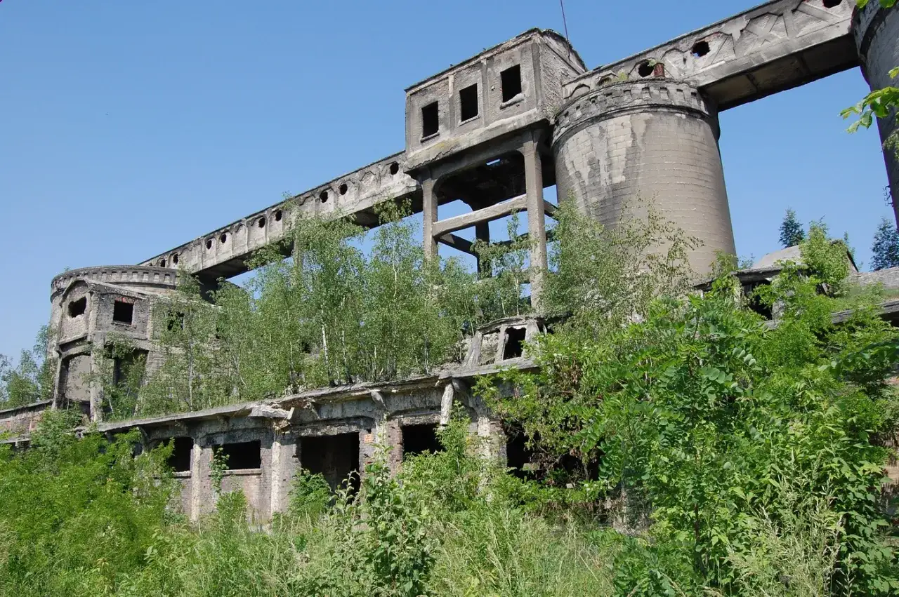 Opuszczona cementownia, zarośnięta zielenią, przypomina o czasach, kiedy wynaleziono cement i zaczęto budować potężne konstrukcje.
