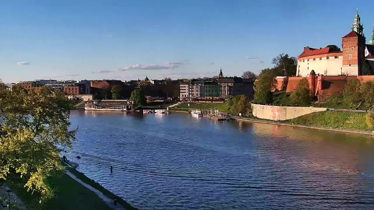 Widok na Wisłę i Wawel, jedne z najładniejszych miejsc w Krakowie. Słoneczny dzień, błękitne niebo i spokojna rzeka.