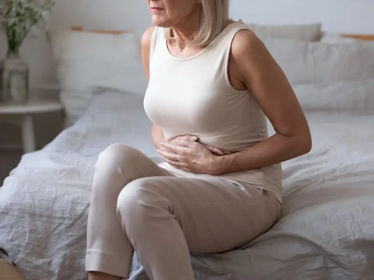 Kobieta z rękami na brzuchu, cierpiąca. Czy to objawy emetofobii? Co to jest i jak sobie z tym radzić?