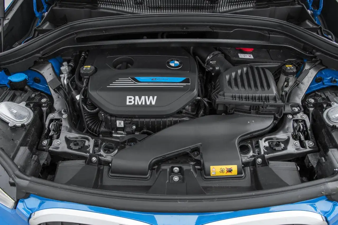 Silnik BMW X1 F48, widok z góry. Czarna pokrywa silnika z logo BMW i napisem 