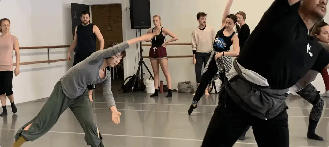 Grupa ludzi ćwiczy taniec w sali. To inspiracja, jak zostać tancerzem, poprzez ruch i pasję.