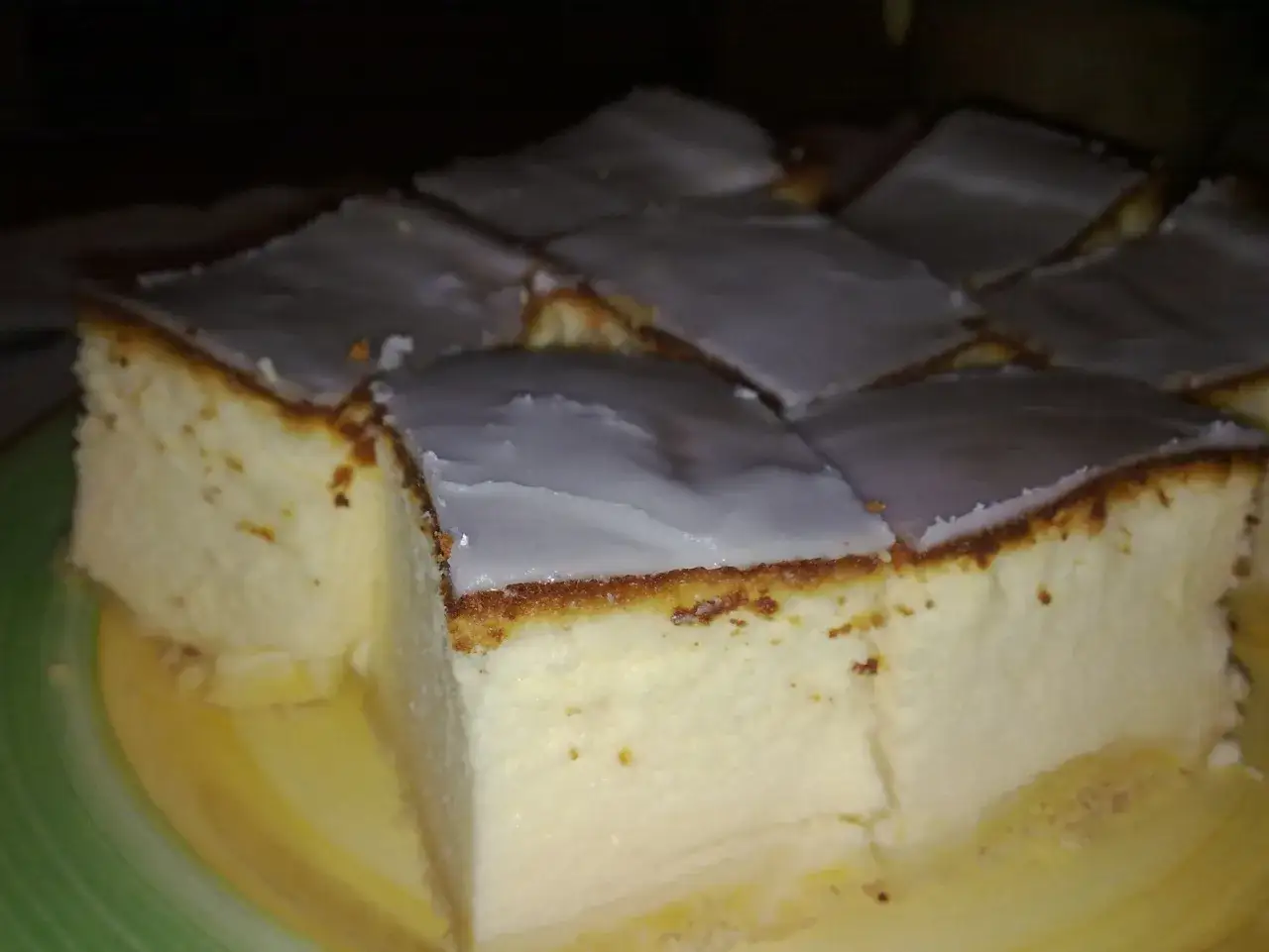 Puszysty sernik z mlekiem, pokrojony w kostkę, z lukrem na wierzchu. Idealny na deser.