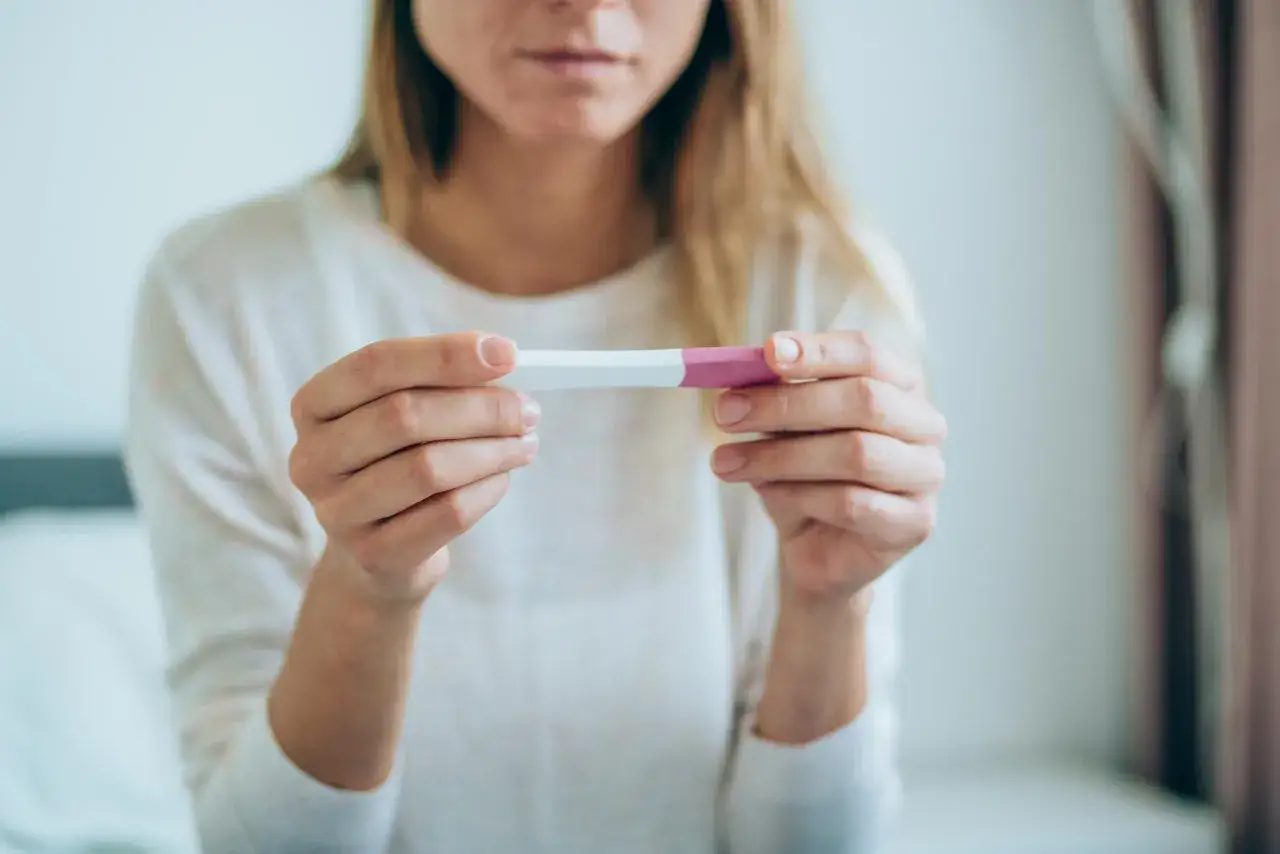Kobieta trzyma test ciążowy, czekając na wynik. Czy to będzie najlepszy test ciążowy, który zmieni jej życie?