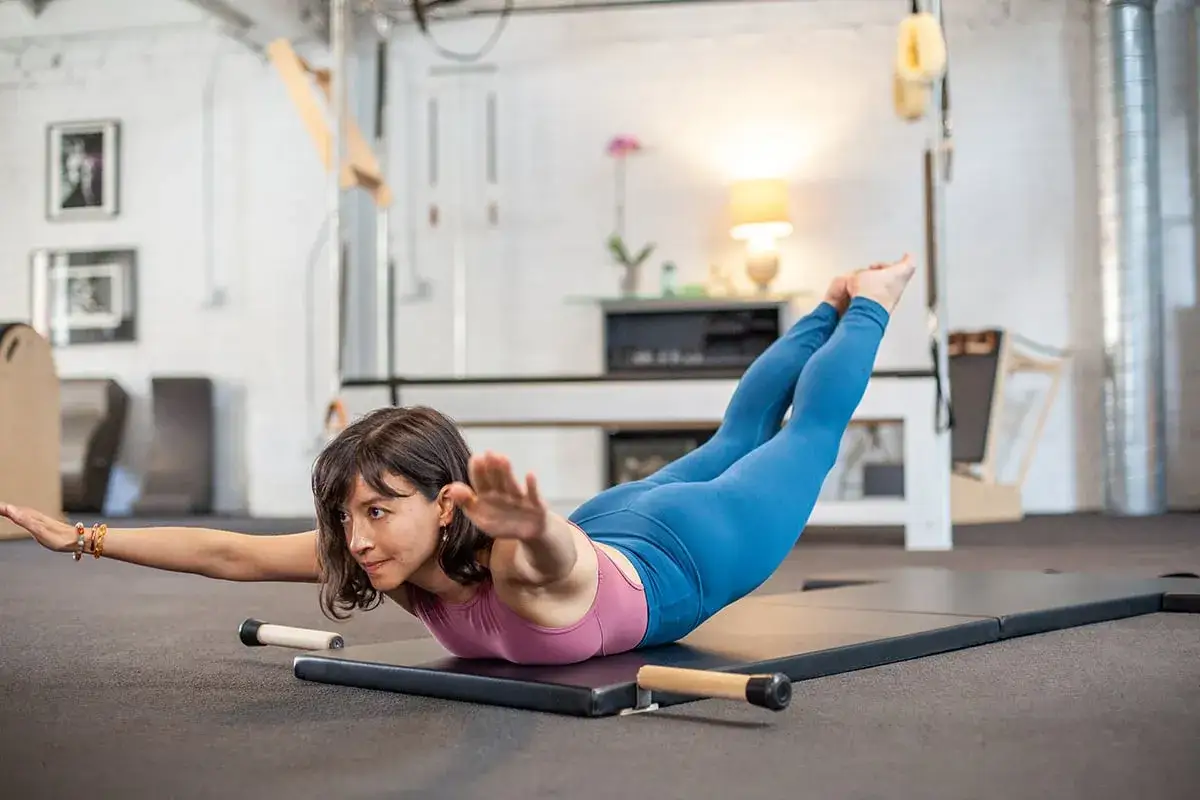 Kobieta wykonuje ćwiczenia na mięśnie głębokie, leżąc na macie i unosząc ciało.