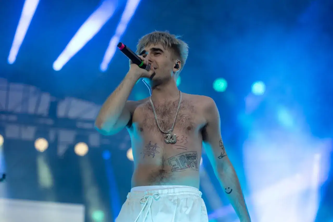 Artysta z tatuażami na klatce piersiowej śpiewa do mikrofonu. Na szyi ma gruby łańcuch. Nie wiadomo, ile lat ma Mata.