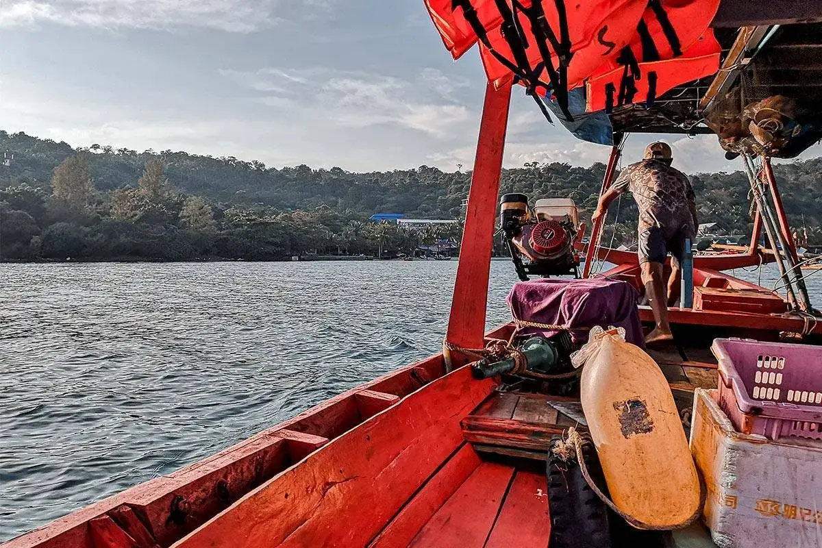 Rejs łodzią po wodach Kambodży, w kierunku wyspy Koh Rong. Widok na zielone wzgórza i morze.