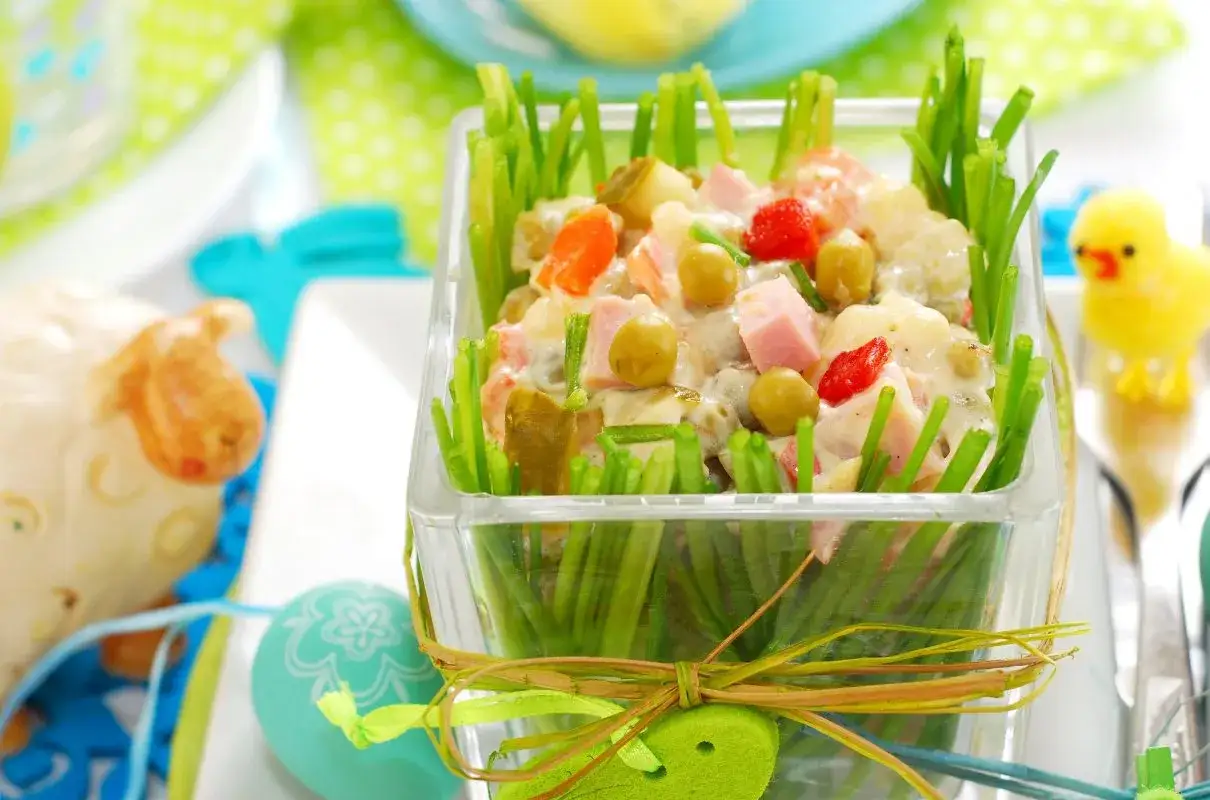 Sałatka jarzynowa w wiosennej odsłonie, idealna inspiracja, co ugotować na Święta Wielkanocne. Dekoracja z zielonej cebulki dodaje świeżości.
