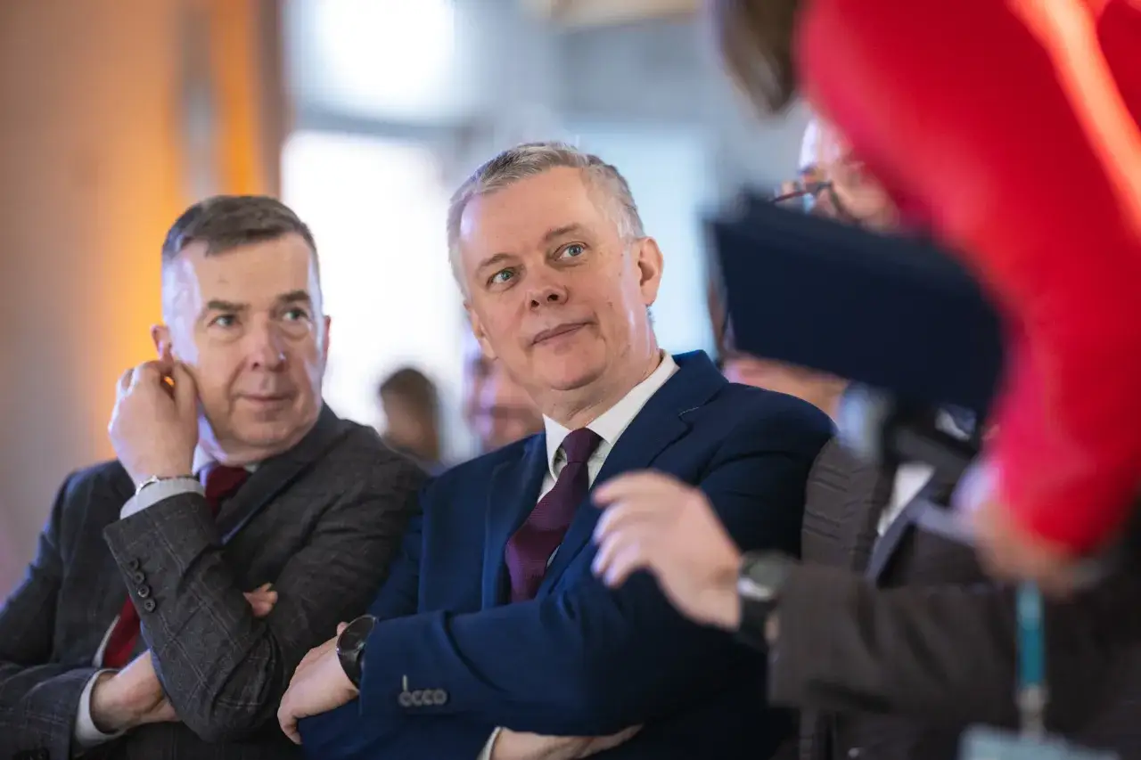 Tomasz Krzysztof Siemion w granatowej marynarce słucha uważnie, siedząc obok kolegi w kratę.