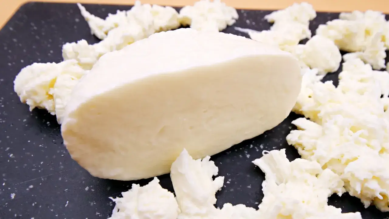 Kawałek sera mozzarella otoczony jest postrzępionymi kawałkami, co może sugerować, czy ser mozzarella jest tłusty.