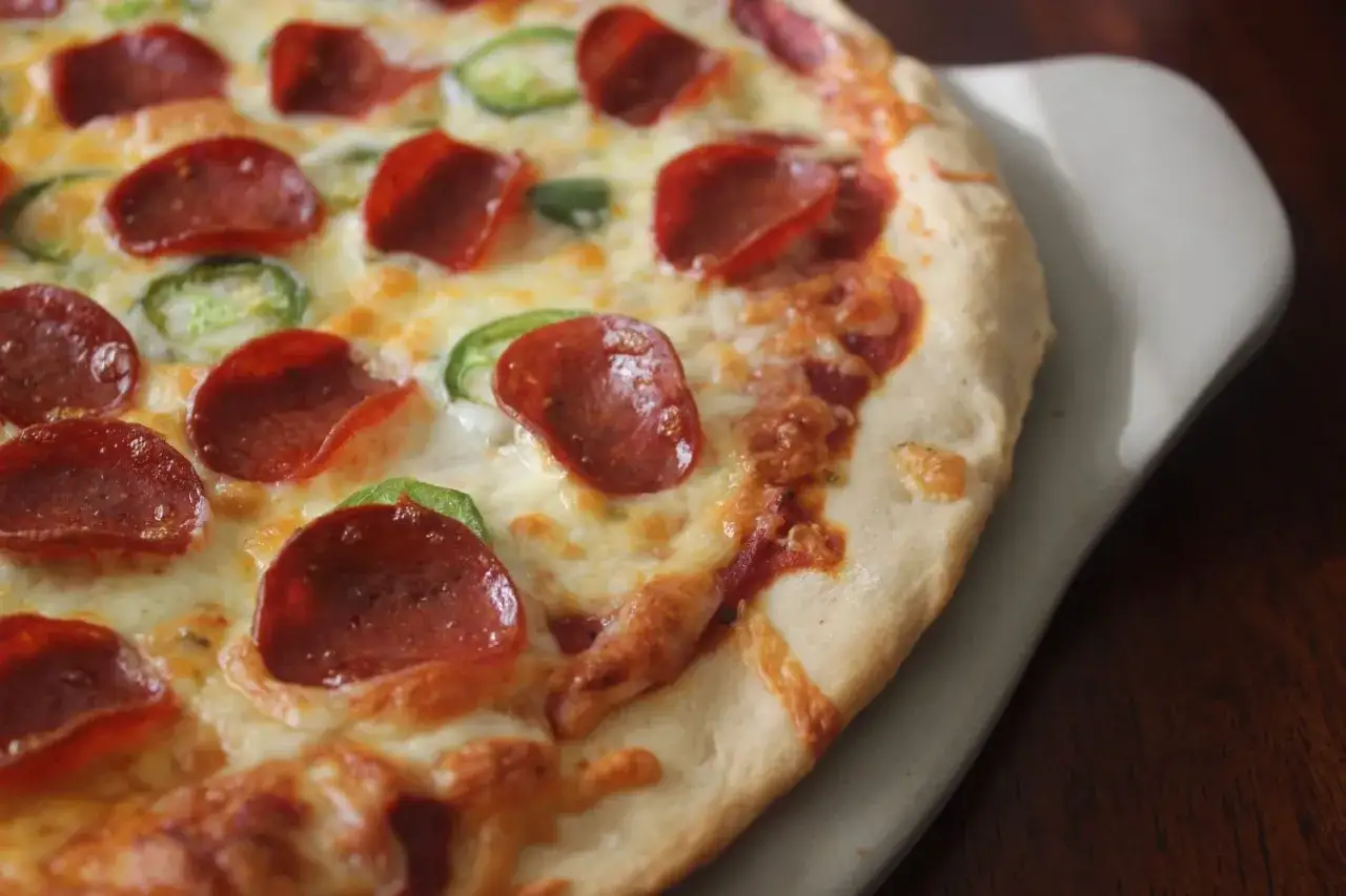 Pyszne ciasto na pizzę bez wyrastania z pepperoni i papryczkami jalape&ntilde;o, zapieczone z serem.