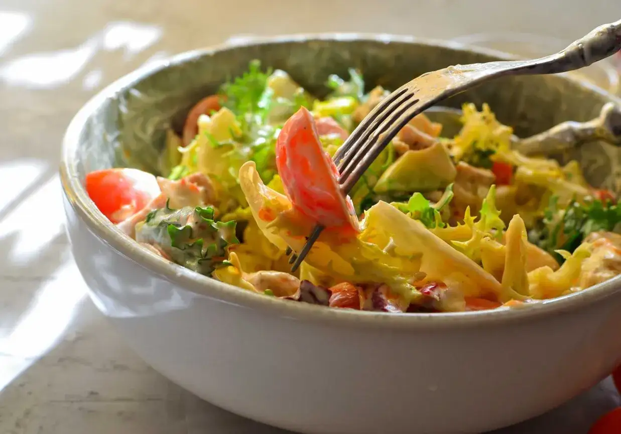 Pyszna surówka z sałaty lodowej, pomidorów i awokado, polana kremowym sosem. Idealna na lekki posiłek.