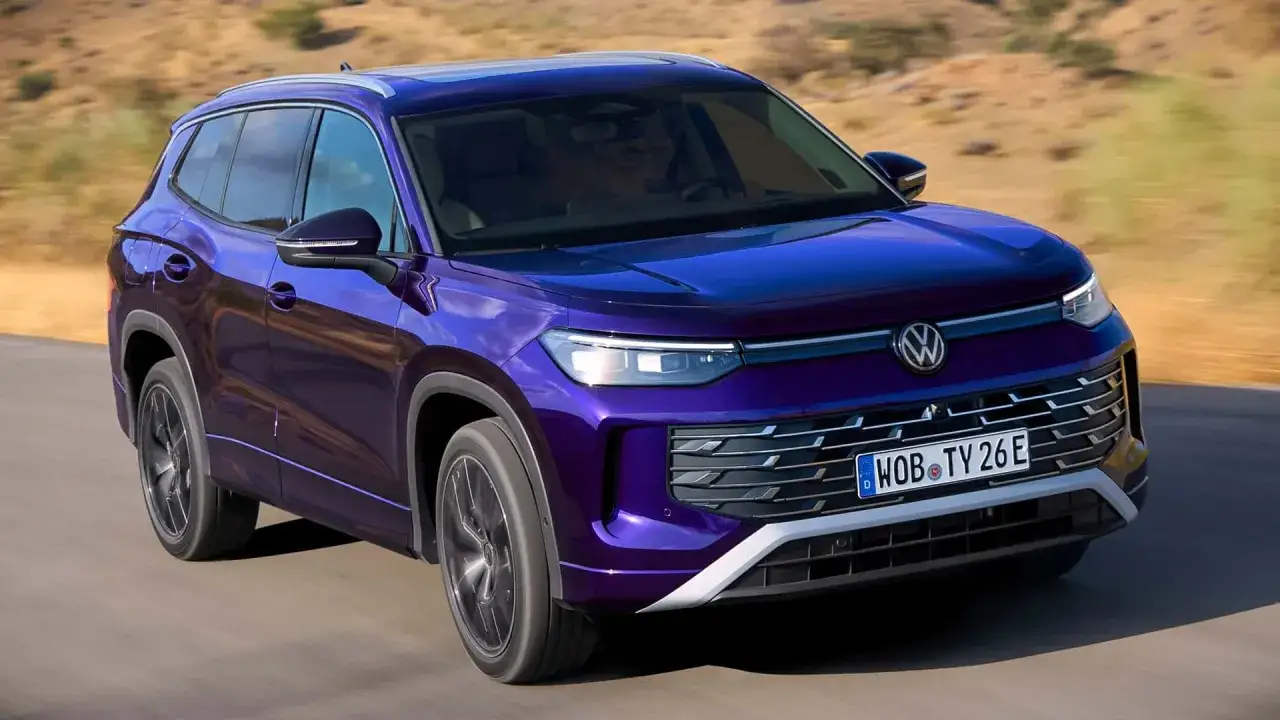 Fioletowy Volkswagen Tayron VW jedzie po drodze.