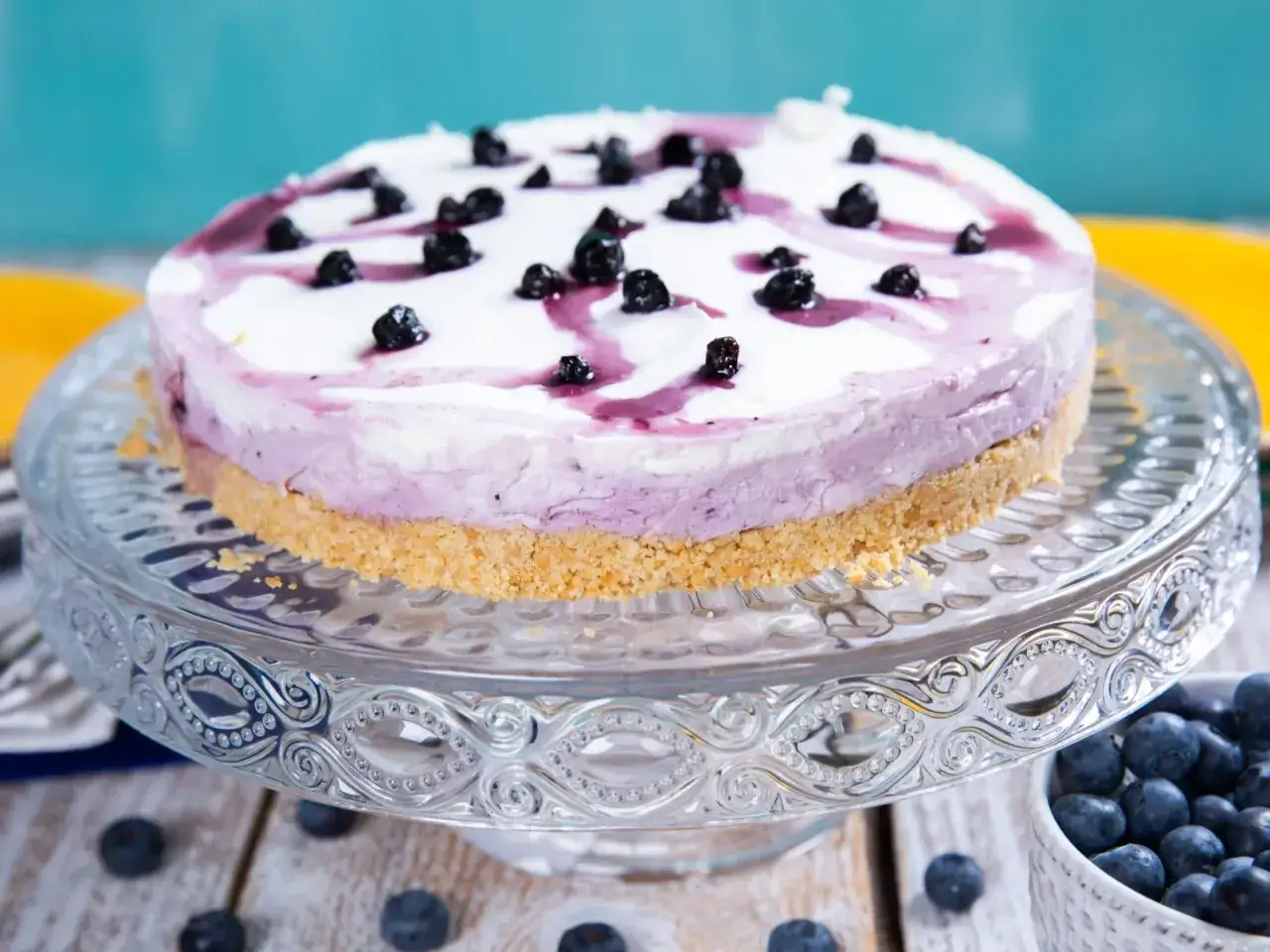 Pyszny sernik z jogurtu naturalnego z jagodami, ozdobiony polewą i świeżymi owocami. Idealny deser na letnie popołudnie.