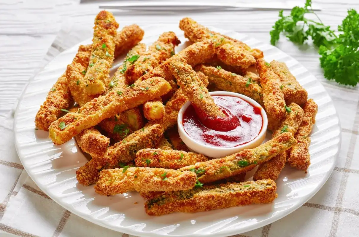 Chrupiące frytki z cukinii w panierce, podane z ketchupem. Idealna przekąska dla każdego!