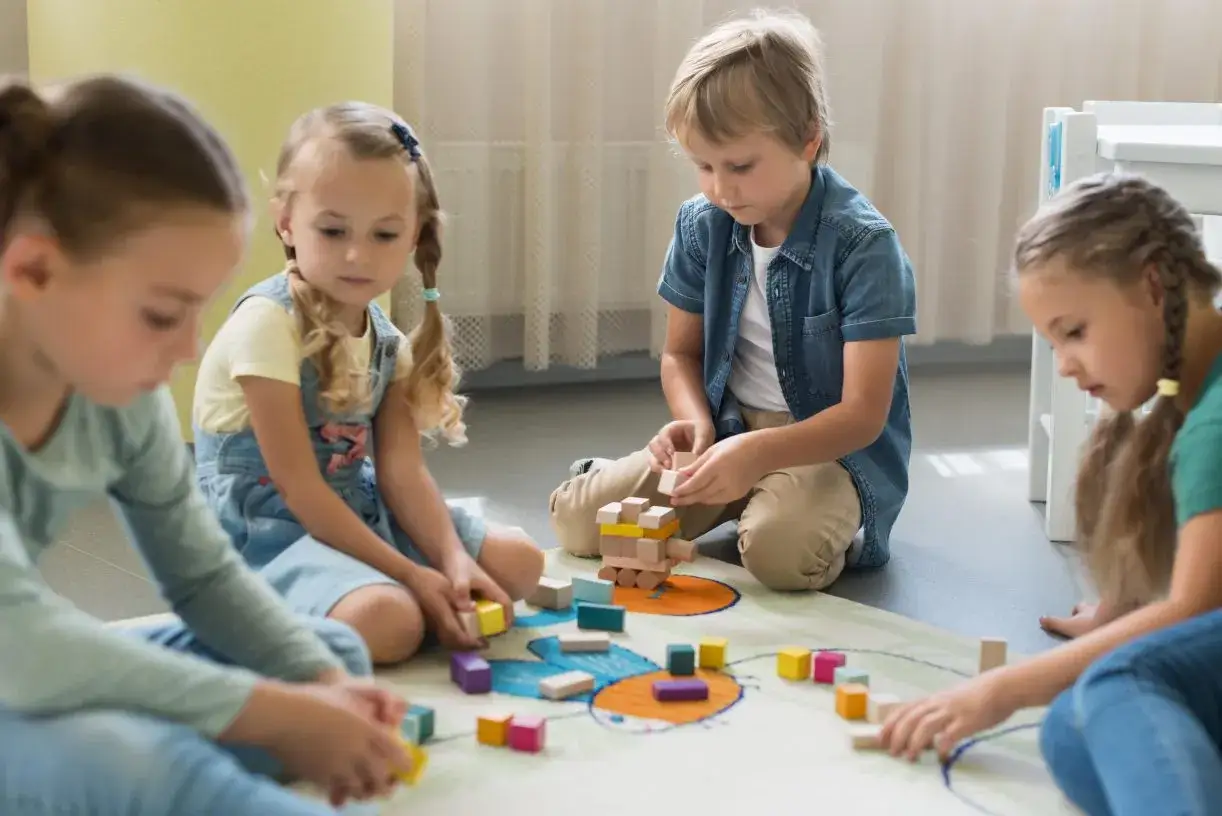 Dzieci budują wieżę z klock&oacute;w, bawiąc się w przedszkolu. Wesołe, stare zabawy przedszkolne.