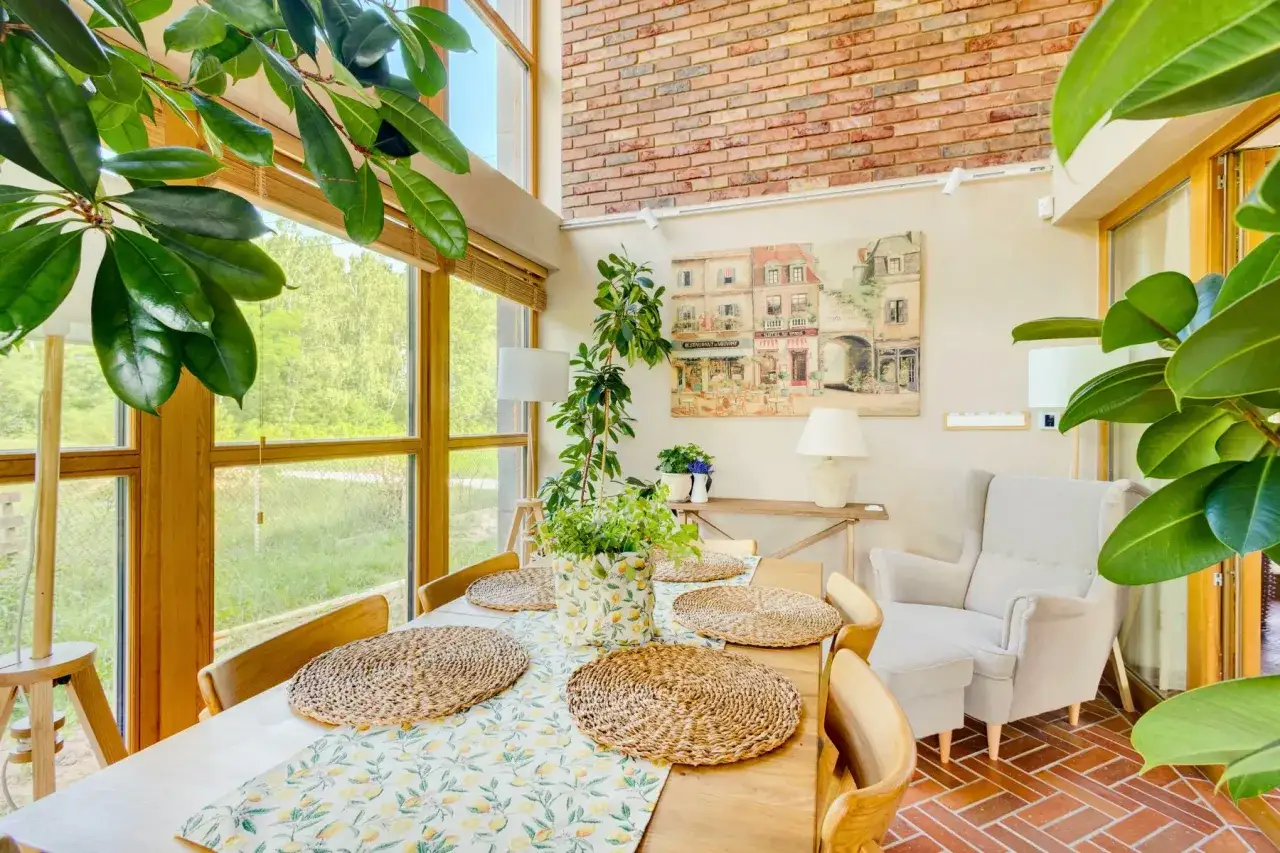 Przytulny salon w wiejskim stylu z drewnianym stołem, plecionymi podkładkami i bujną zielenią. Obraz przedstawia paryską uliczkę.