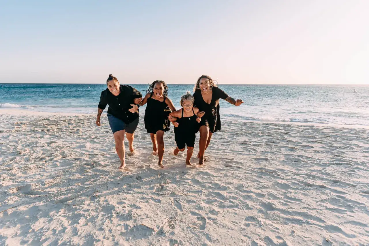 Rodzina biegnie plażą, trzymając się za ręce. Radość i beztroska – tak pozować do zdjęć na wakacjach!