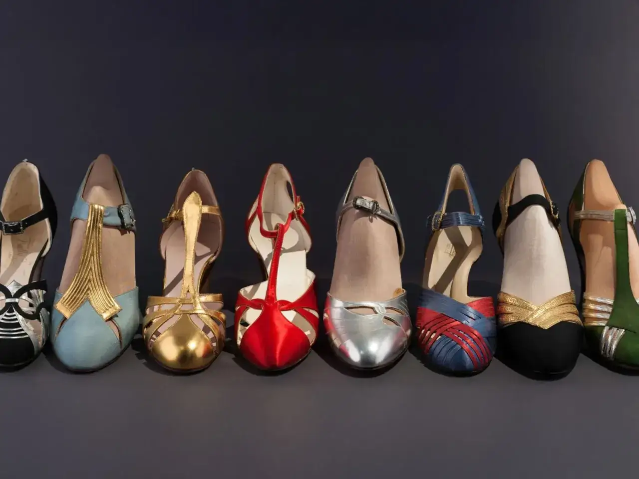 Rząd kolorowych butów na obcasie, w tym czarne, błękitne, złote, czerwone, srebrne, niebiesko-czerwone, czarno-złote i zielone. To są właśnie te słynne high heels!
