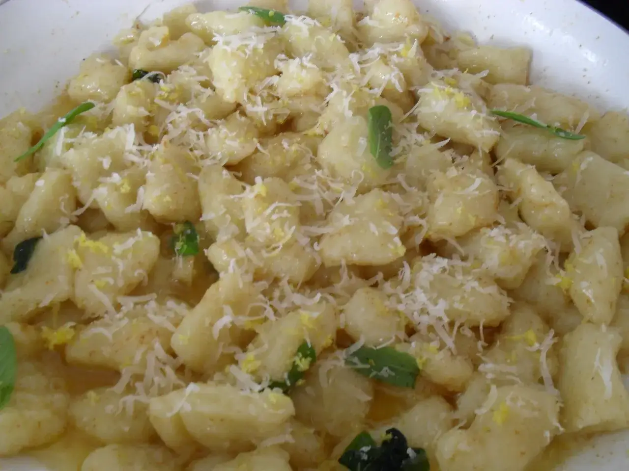 Pyszne gnocchi z delikatnym sosem cytrynowo-maślanym, posypane parmezanem i świeżą bazylią.