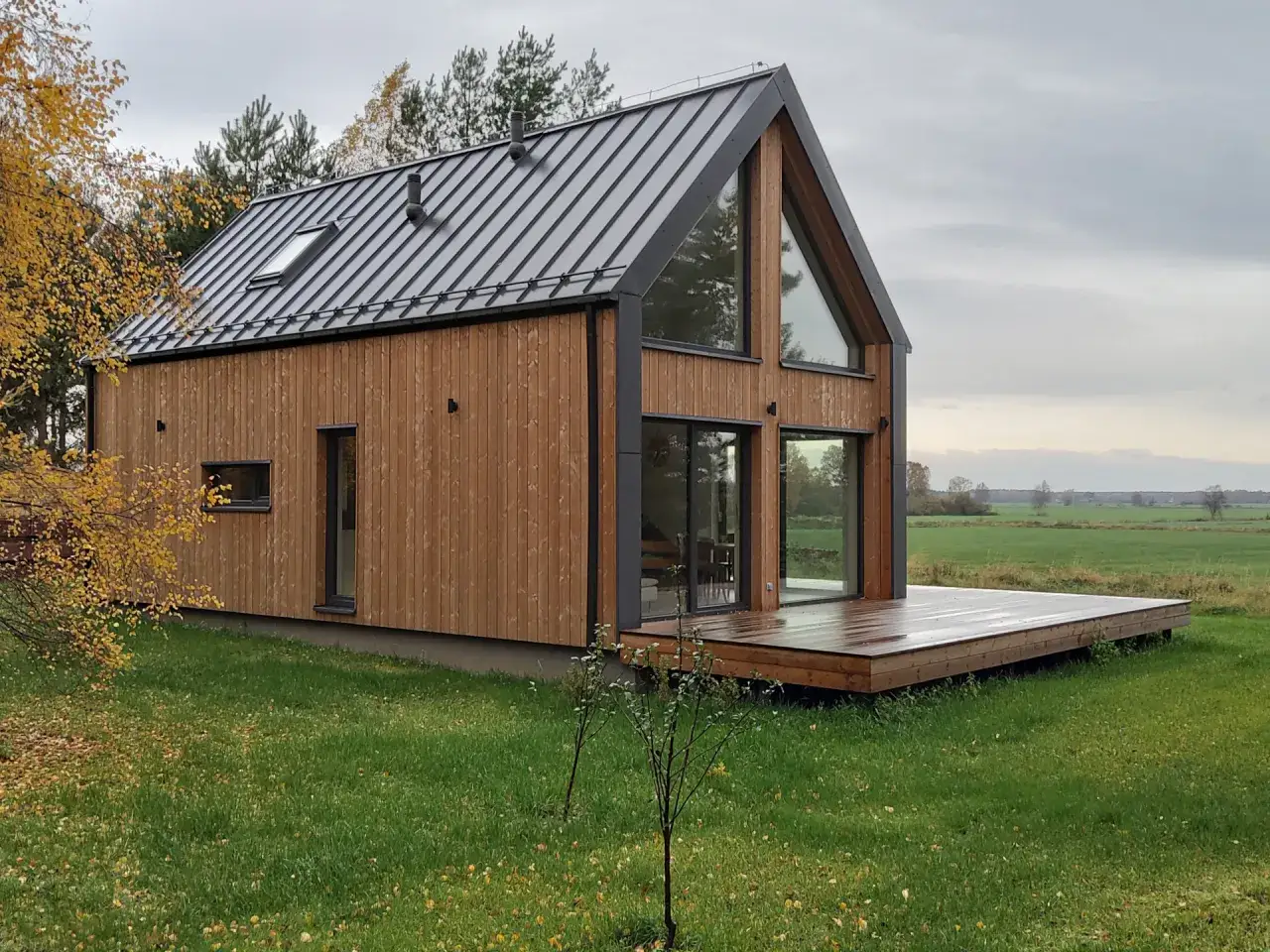 Nowoczesny dom modułowy z drewnianą elewacją i dużymi oknami. Czy dom modułowy jest tańszy? Ten przykład sugeruje, że może być atrakcyjną opcją.