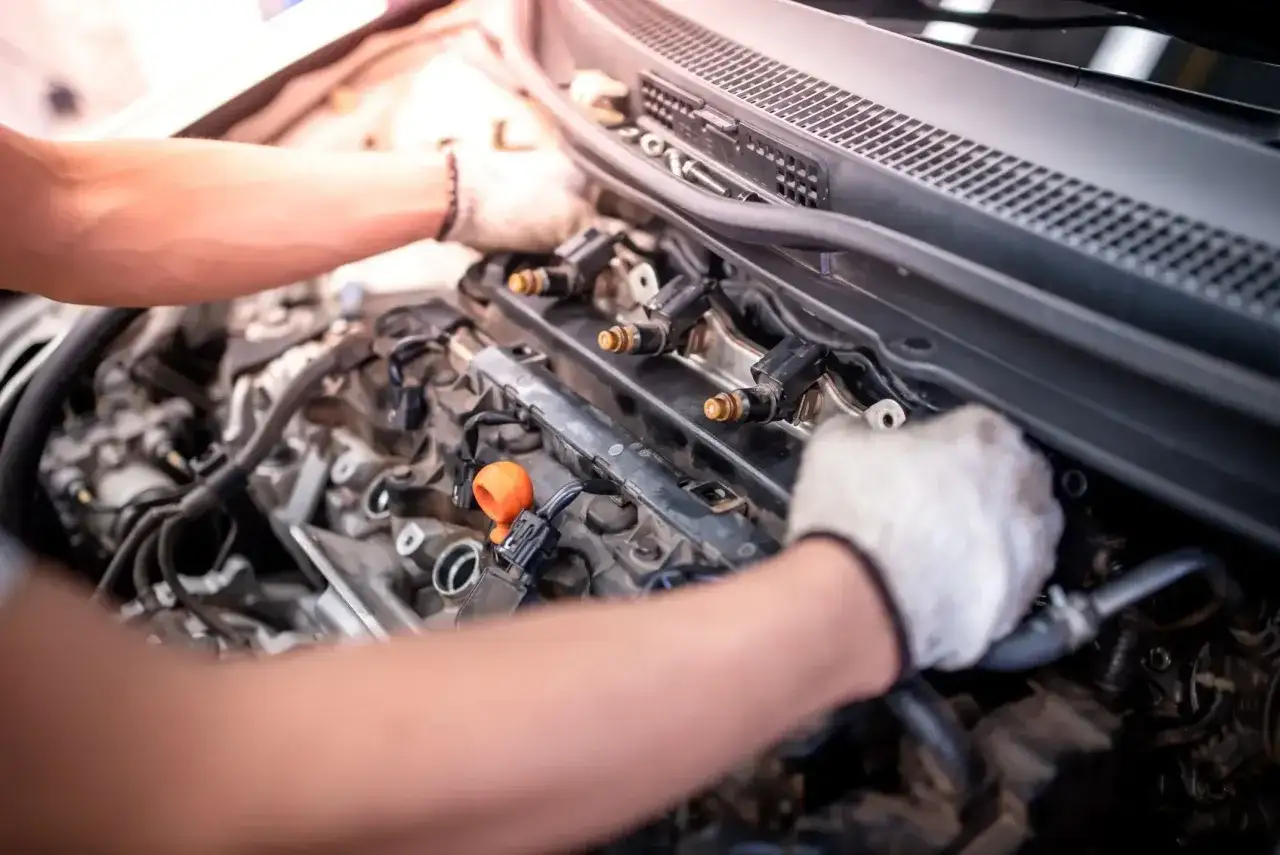 Mechanik w białych rękawiczkach pracuje przy silniku. Silnik bierze olej, ale nie kopci, co może oznaczać problem z uszczelkami lub pierścieniami.