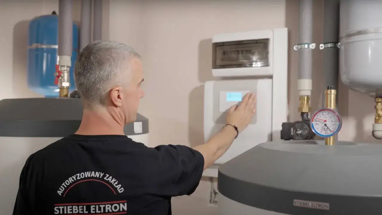 Serwisant sprawdza wyświetlacz urządzenia Stiebel Eltron, być może szukając kodów błędów.