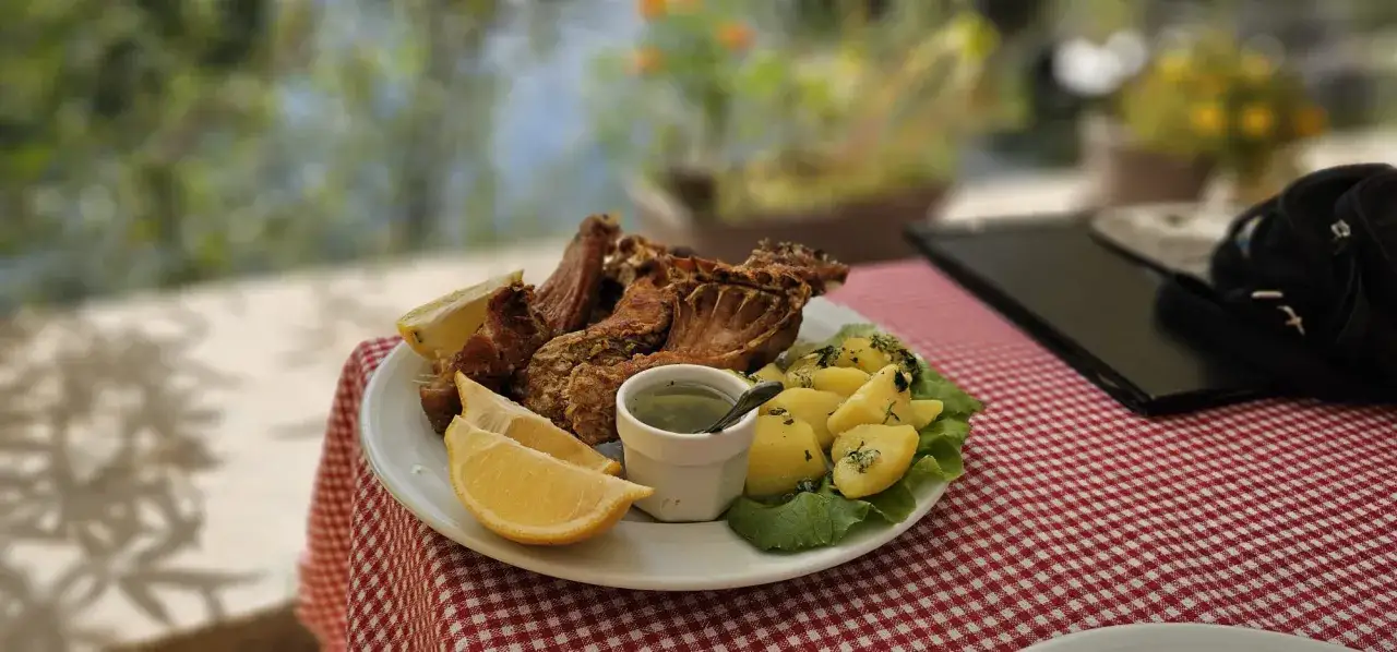 Pyszne czarnog&oacute;rskie jedzenie: pieczone mięso, ziemniaki i cytryna na talerzu.