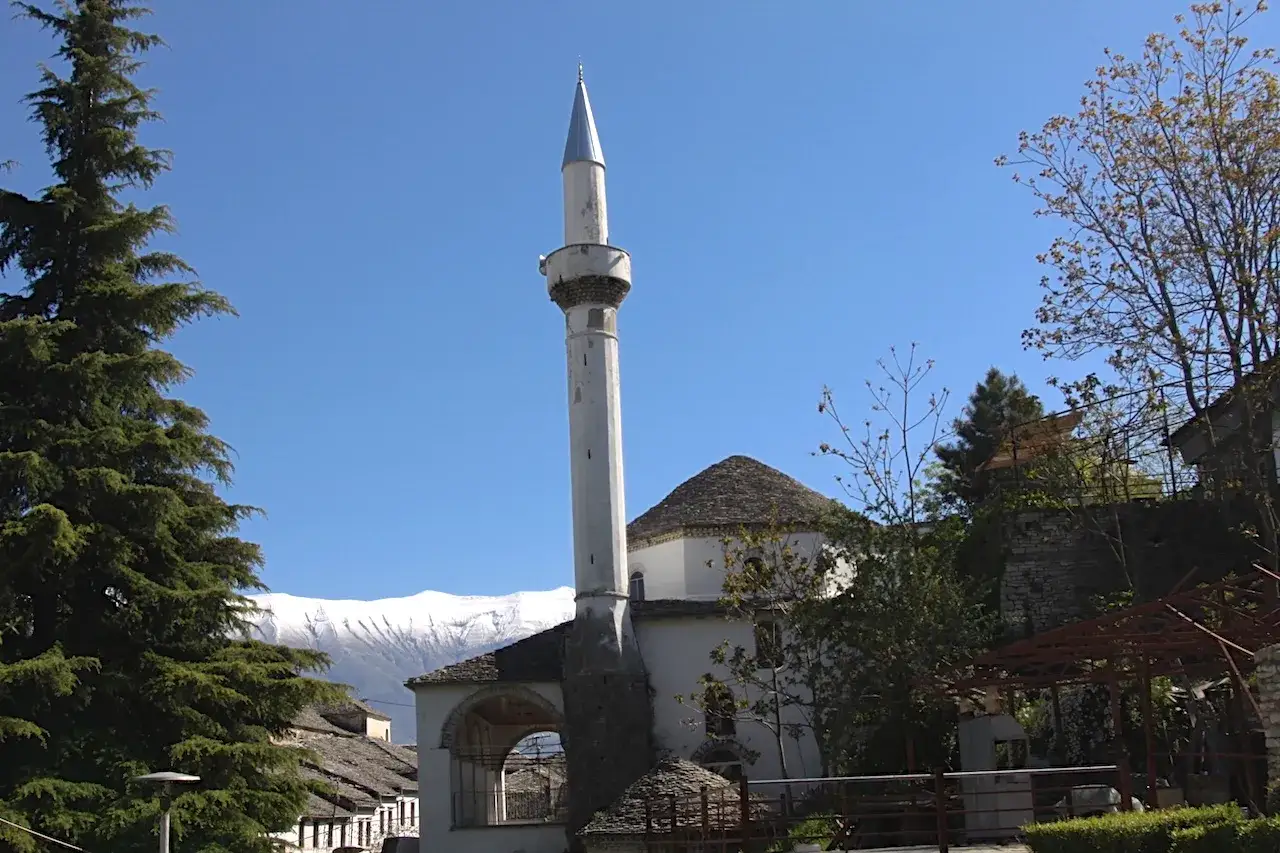 Minaret i meczet w Albanii, symbolizujące bogactwo religii tego kraju. W tle ośnieżone góry.
