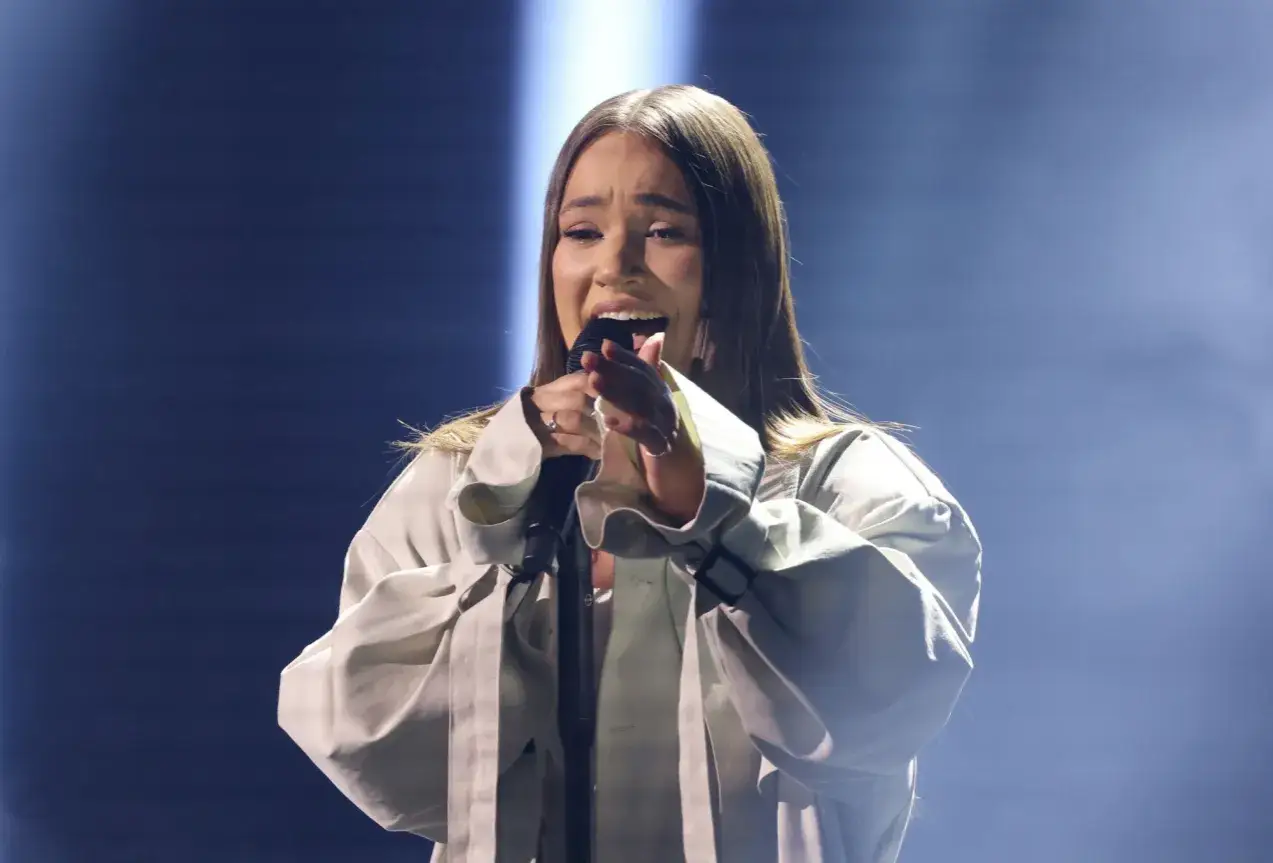 Młoda artystka śpiewa do mikrofonu. Czy to ona wie, kto decyduje o tym które piosenki trafią do finałowego odcinka?