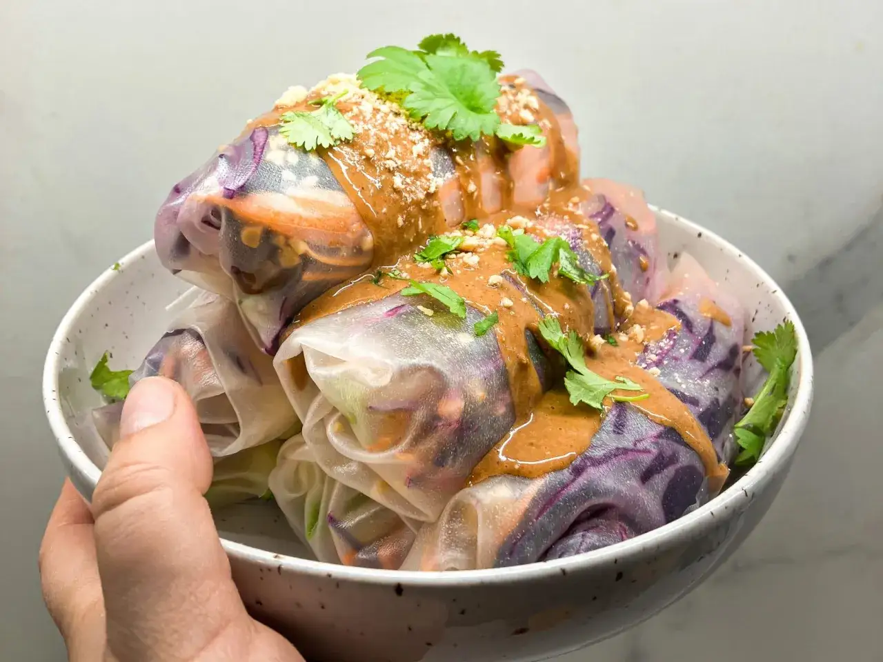 Sajgonki z warzywami polane kremowym sosem orzechowym, posypane orzeszkami i świeżą kolendrą. Pyszny sos orzechowy do sajgonek.