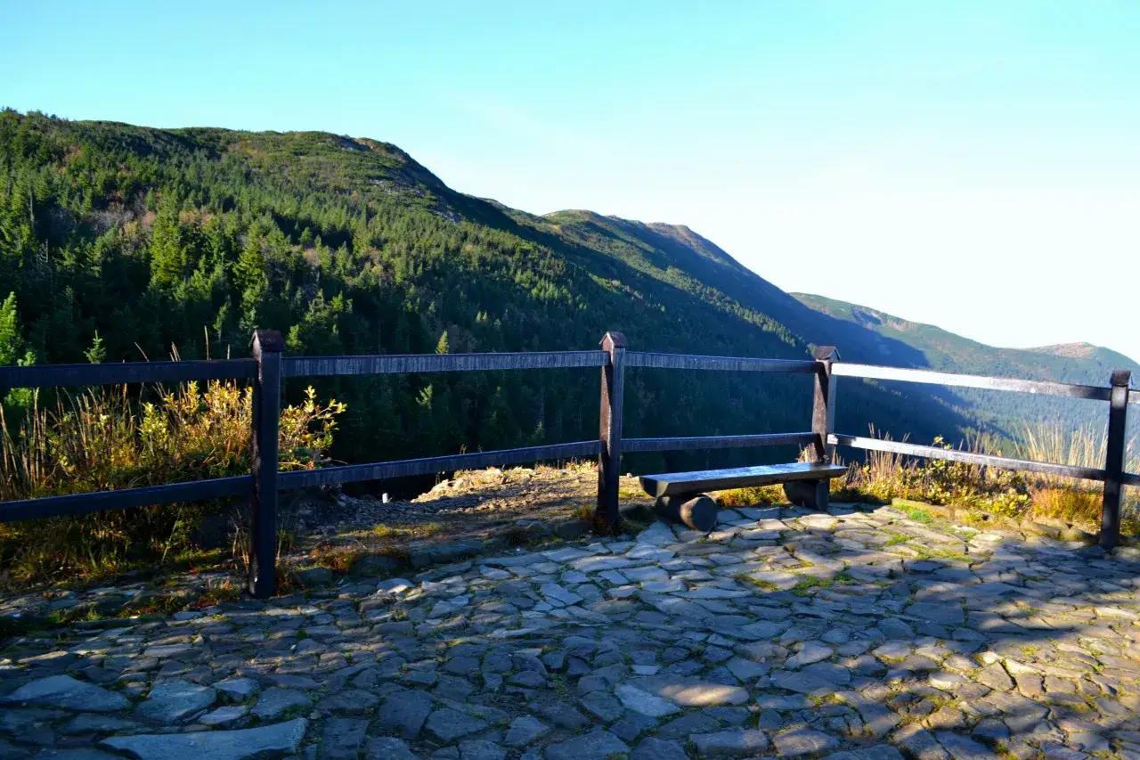 Kamienna ścieżka i ławka z widokiem na zalesione zbocza Babiej G&oacute;ry. Kt&oacute;ry szlak na Babią G&oacute;rę najładniejszy? Ten z takimi widokami na pewno!