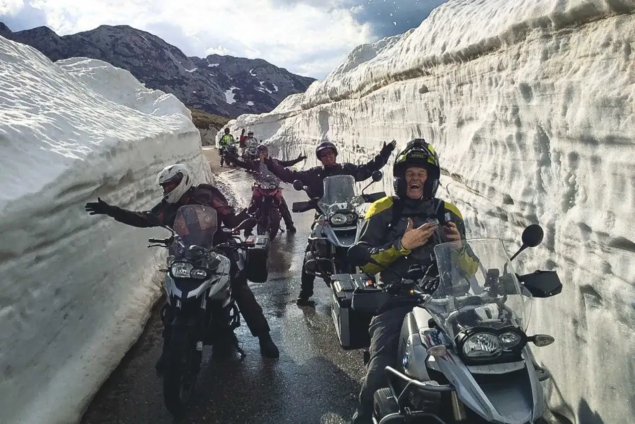 Ekscytująca podr&oacute;ż motocyklem po Europie przez zaspy śnieżne. Uśmiechnięci motocykliści cieszą się przygodą.