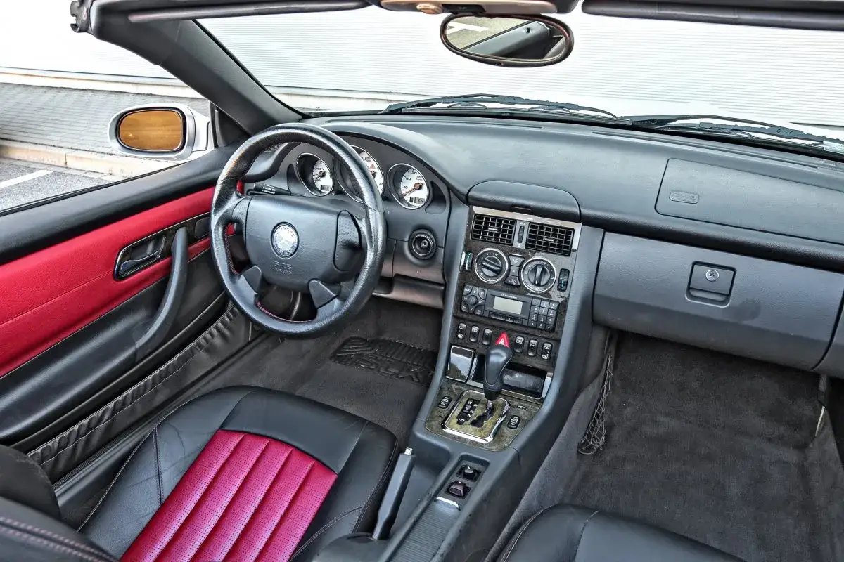 Wnętrze sportowego Mercedesa Benz SLK z czarno-czerwonymi skórzanymi fotelami i deską rozdzielczą.
