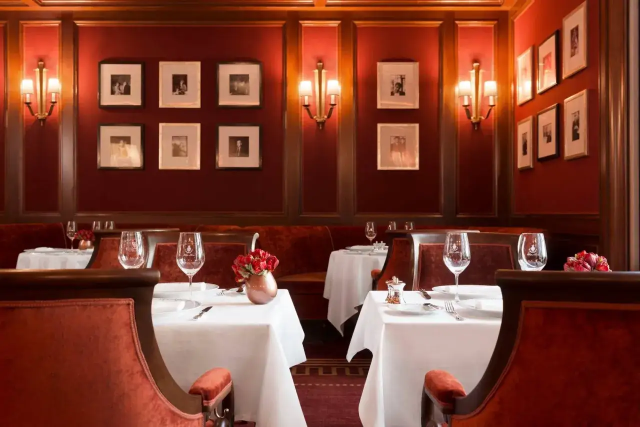 Elegancka restauracja w hotelu Ritz w Paryżu. Czerwone aksamitne fotele i obrusy tworzą luksusową atmosferę.