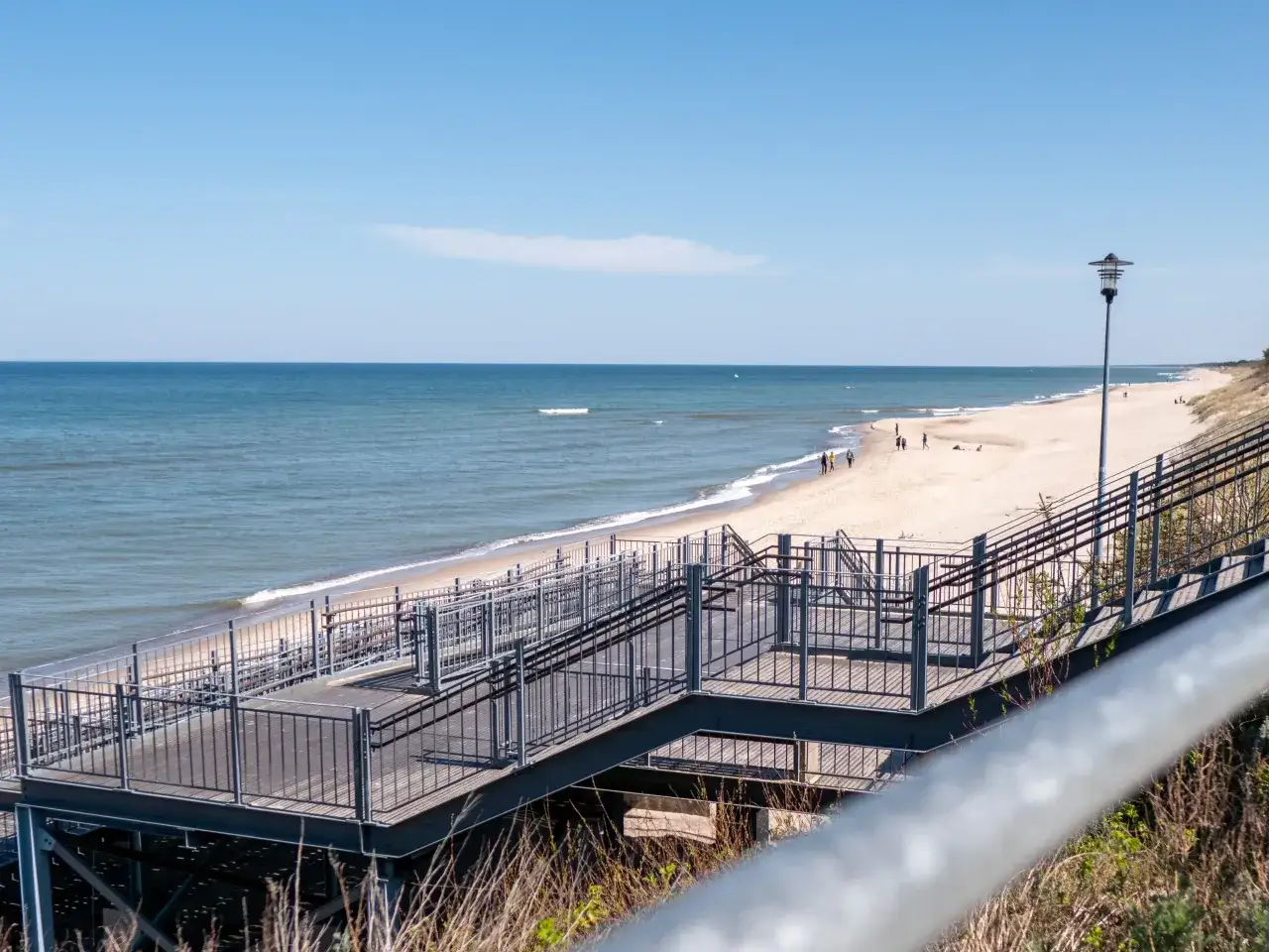 Widok na plażę i morze. Schody prowadzą na wydmy. Zastanawiasz się, ile kilometrów jest z Mielna do Kołobrzegu?